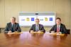 Three people at a table, signing the MOU