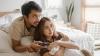 Asian couple watching television in a bedroom.