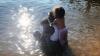 Ricki with her two granddaughters, Belle and Leia sitting in water by a beach