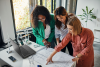 Three woman looking at blueprints together