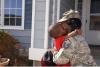 Soldier hugging son in front of house