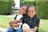Two African American children ( a boy and a girl) are seated, smiling and holding an Aflac duck.