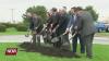 Group of people in suits using shovels to dig up some dirt