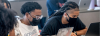 two Black Howard University students in masks work on laptops
