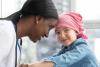 Female doctor is bumping heads with a young cancer patient.