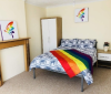 safe house bedroom with a rainbow flag on the bed and rainbow art on the walls