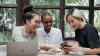 Three female influencers seated at a table in front of a laptop.